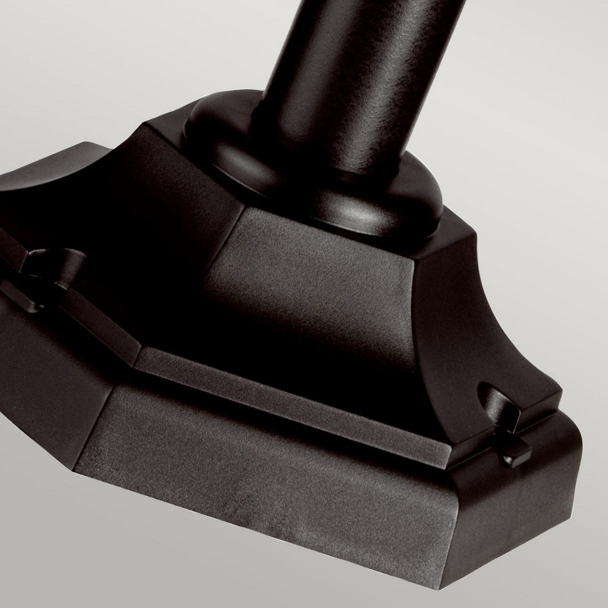 Close-up of the base of the Kinsale 1 Light Pillar Light in black, highlighting its ornate and symmetrical design with a smooth, glossy surface. The outdoor light's base is crafted with clean lines and subtle detailing against a neutral background, emphasizing its corrosion-resistant properties.