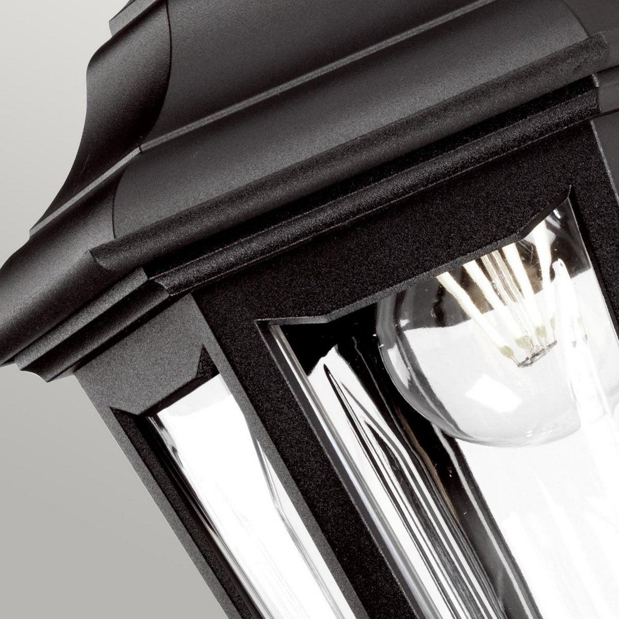 The Kinsale-2 1 Light Outdoor Wall Light in black showcases a traditional design that is ideal for coastal settings. The clear glass enclosure unveils a visible bulb, emphasizing its corrosion-proof quality. Mounted against a pale backdrop, it highlights its classic and elegant design features.