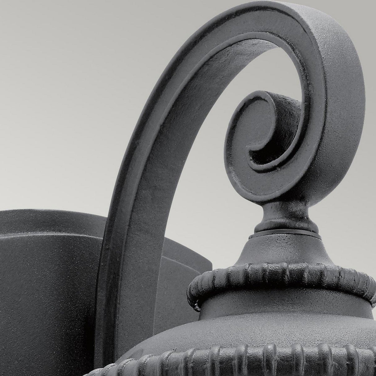 The Admirals Cove Outdoor 1 Light Small Wall Lantern in black showcases intricate detailing with a spiral scroll and ridged accents, set against a light gray background. Expertly crafted, this fixture is IP44 rated for durability.