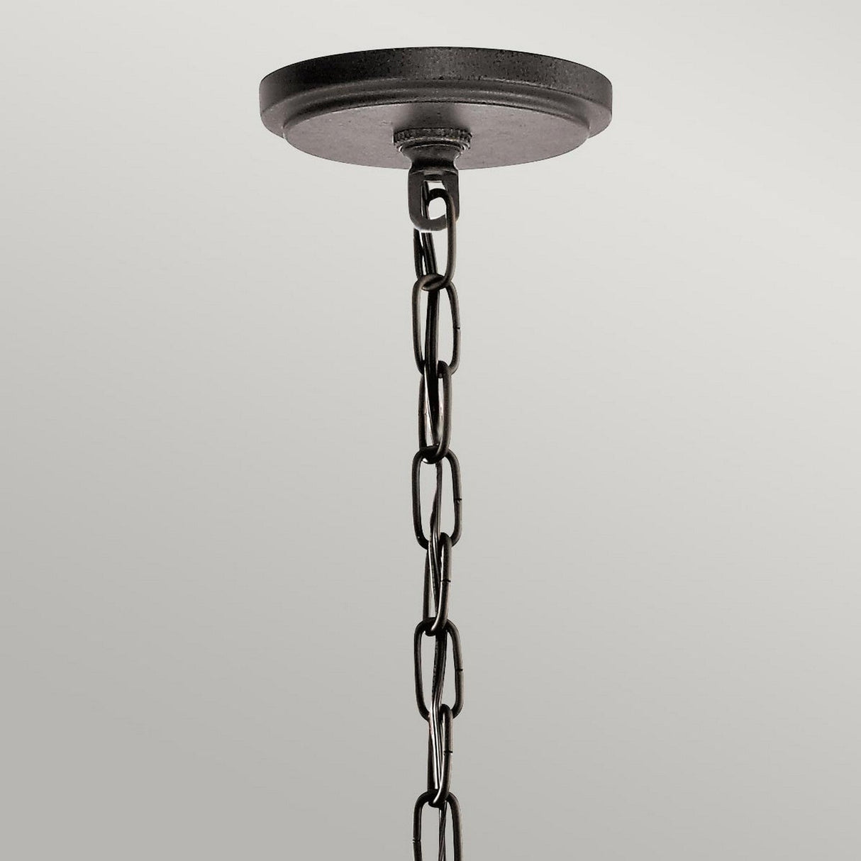 The Ahrendale 4 Light Chandelier in Grey exudes rustic charm with its black metal ceiling canopy and a chain composed of repeated oval links, creating an industrial look reminiscent of Anvil Iron mesh against a plain gray background.