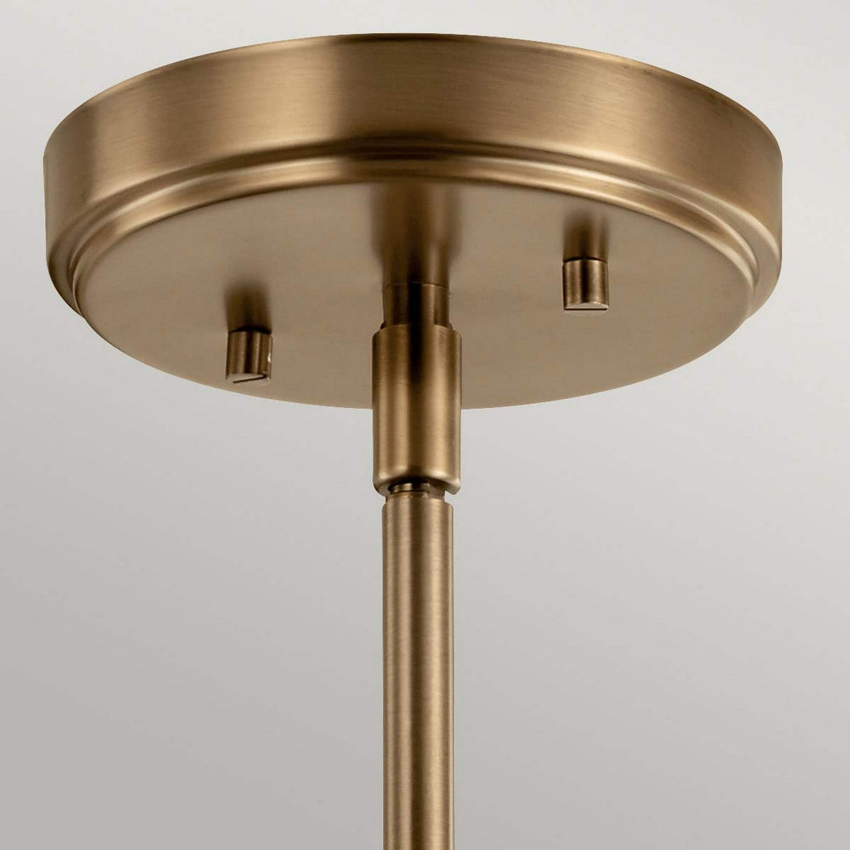 A close-up view of the Aivian 1 Light Pendant in a weathered brass finish showcases its industrial-inspired design. The fixture features a circular base with two decorative screws and a sleek cylindrical rod that extends downward, boasting a smooth, polished surface set against a plain, neutral background.