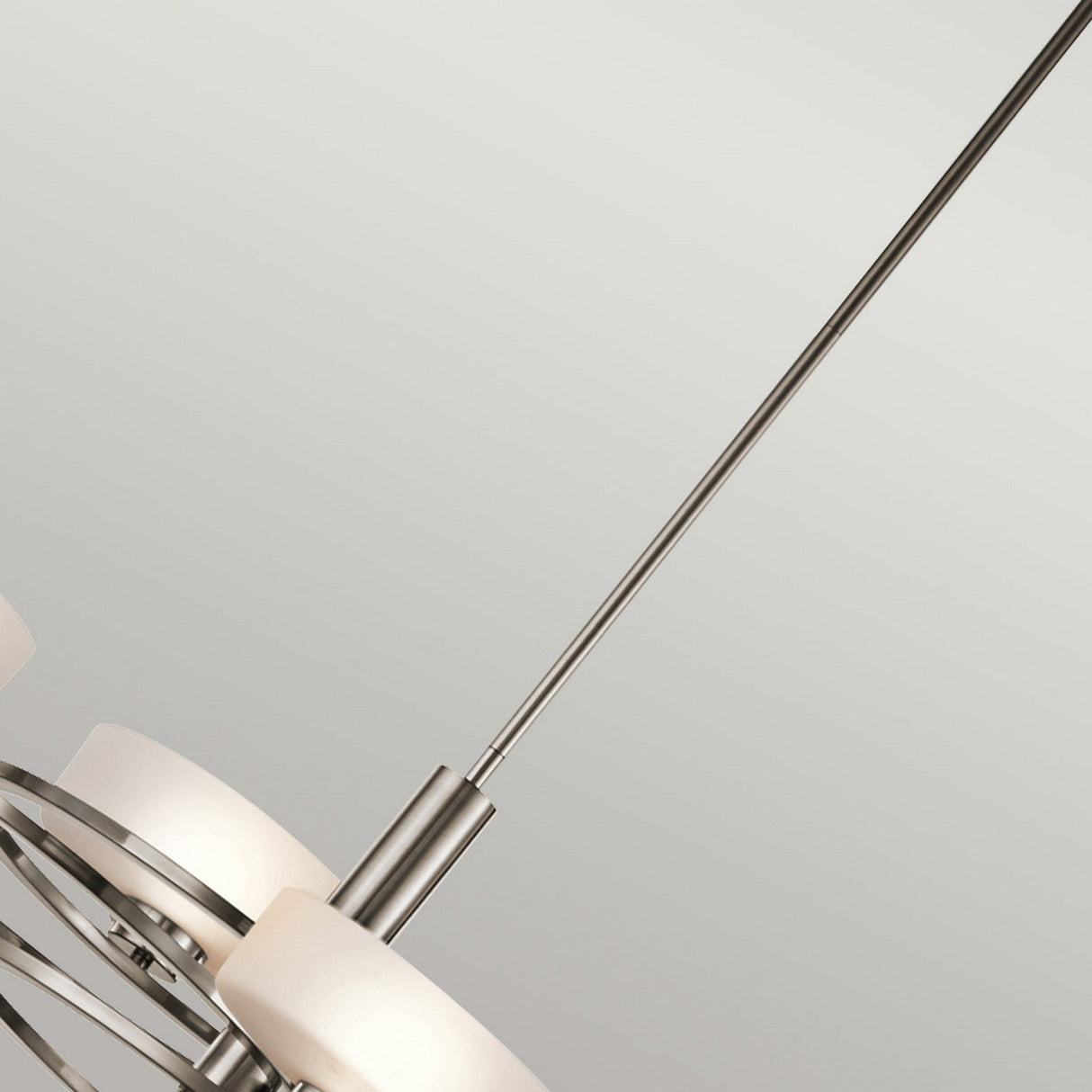 Close-up of the Aleeka 5 Light Chandelier in silver, inspired by celestial design elements. It features five circular frosted glass lampshades resting on a sleek metal frame. This elegant fixture hangs from a straight metal rod against a plain white background, making it an ideal choice for contemporary interiors.