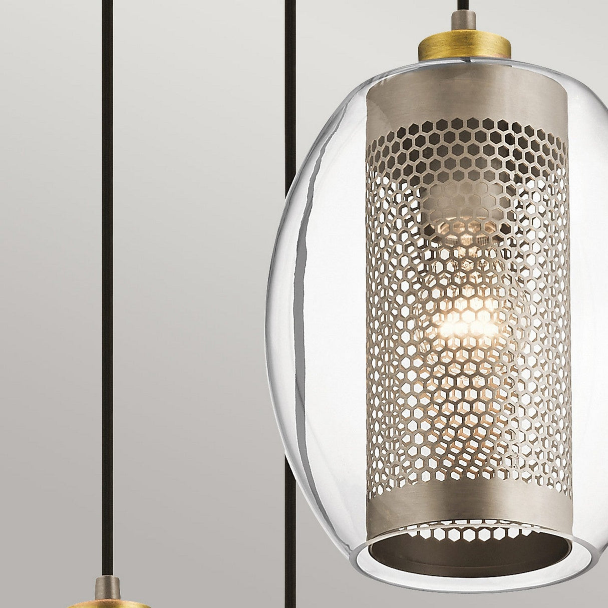 Close-up of the Asher 3 Light Pendant - Silver, showcasing a modern, industrial-inspired design with its cylindrical, perforated metal shade and clear glass cover. The warm glow of the bulb illuminates through the mesh, suspended elegantly from a slender black cord against a neutral backdrop.