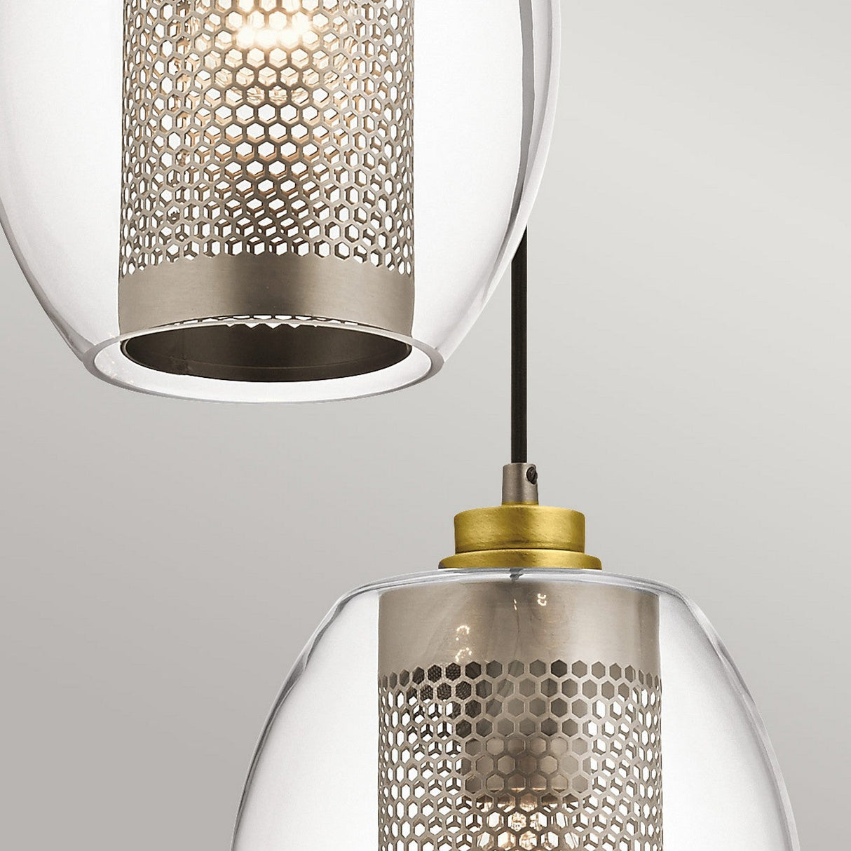 The Asher 3 Light Pendant - Silver features two hanging lights with metal mesh shades and transparent glass covers, offering an industrial-inspired aesthetic that emits a warm glow. The upper light is partially visible, while the lower one is prominently in focus against a simple gray background, highlighting its elegant circular design.