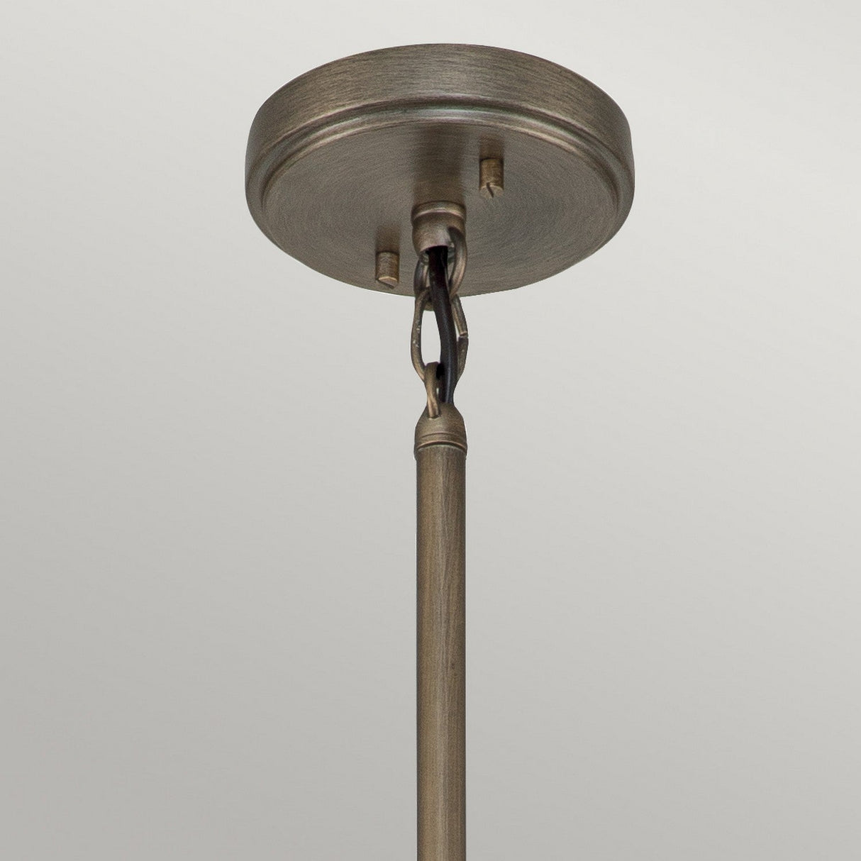 A close-up of the Ashland Bay Outdoor 5 Light Chandelier in burnished bronze showcases its circular base with a vertical rod extending downward, featuring a decorative twisted element that enhances its outdoor chandelier style. The finish has a weathered bronze-like sheen.