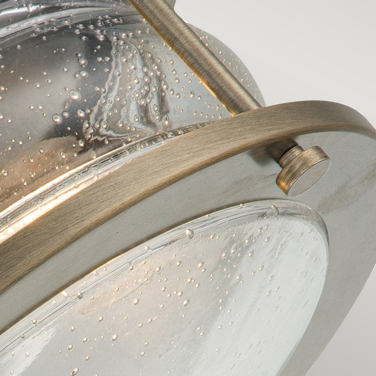 This close-up highlights the Ashland Bay Outdoor 2 Light Outdoor Ceiling Flush in Burnished Bronze. Featuring a brass finish and bubble-textured glass, its Edison-style bulbs emit a warm glow, and the fixture is discreetly secured to the ceiling with a side screw.