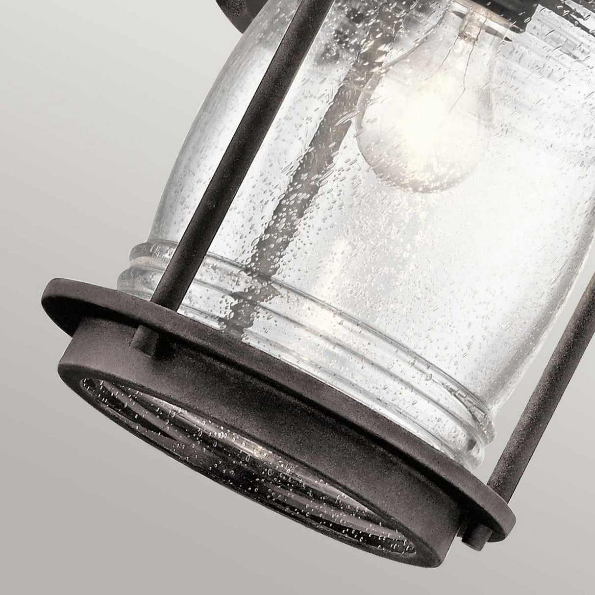 A detailed shot of the Ashland Bay Outdoor 1 Light Large Wall Lantern reveals its vintage charm, showcasing a clear, textured glass encasing an LED Edison bulb. Its weathered zinc frame exudes character, while the gentle glow offers a warm and welcoming atmosphere.