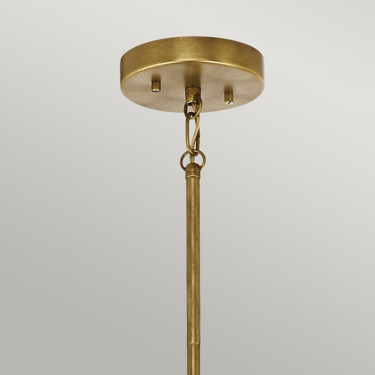 Close-up of the Aster 3 Light Pendant - Brass, showcasing its ribbed glass domes and circular base with a rod suspended by a chain link. The fixture stands out against the plain gray background.