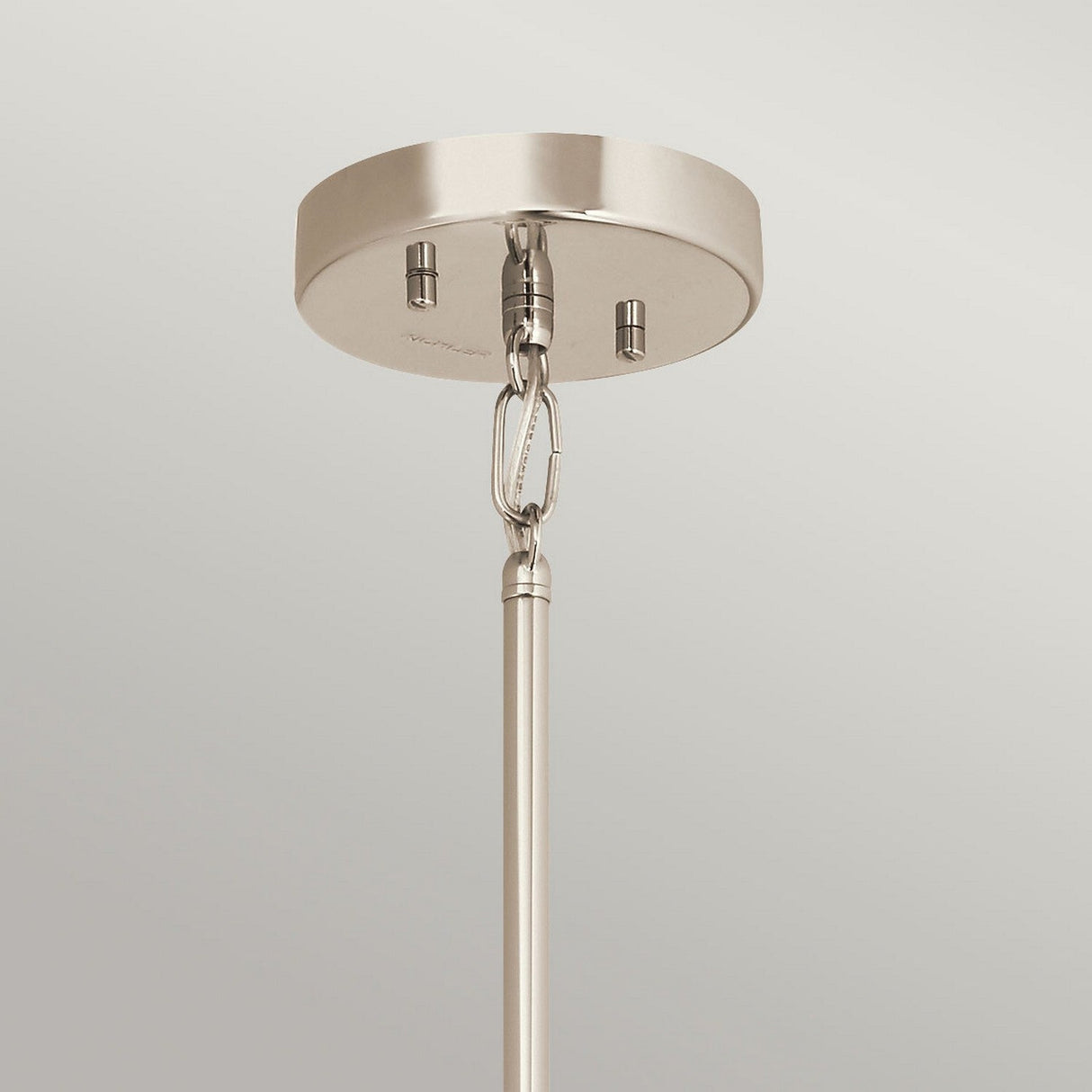A polished nickel ceiling mount with a rod and metal ring, featuring the elegant Aster 3 Light Pendant design. Attached via a hook, its ribbed glass domes add texture against the plain light gray wall.