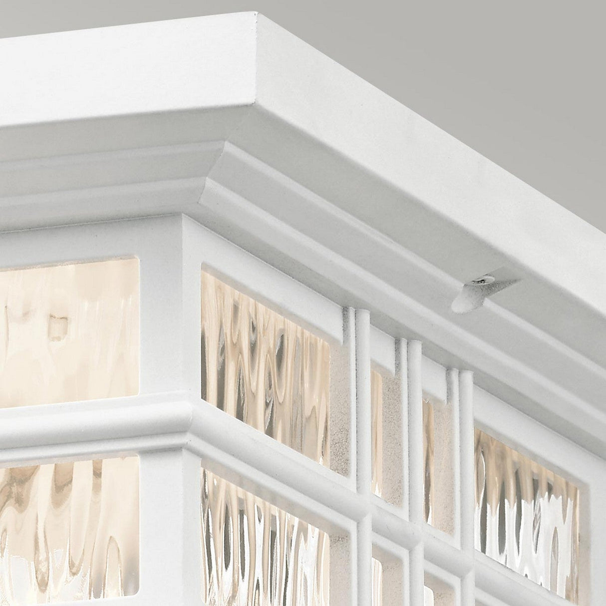 Close-up of the Beacon Outdoor 2 Light Flush in white, with textured glass panels. The fixture boasts a durable finish and decorative trim, featuring glass that diffuses the light for a gentle glow. Its transitional design contrasts beautifully with the plain, light gray background.