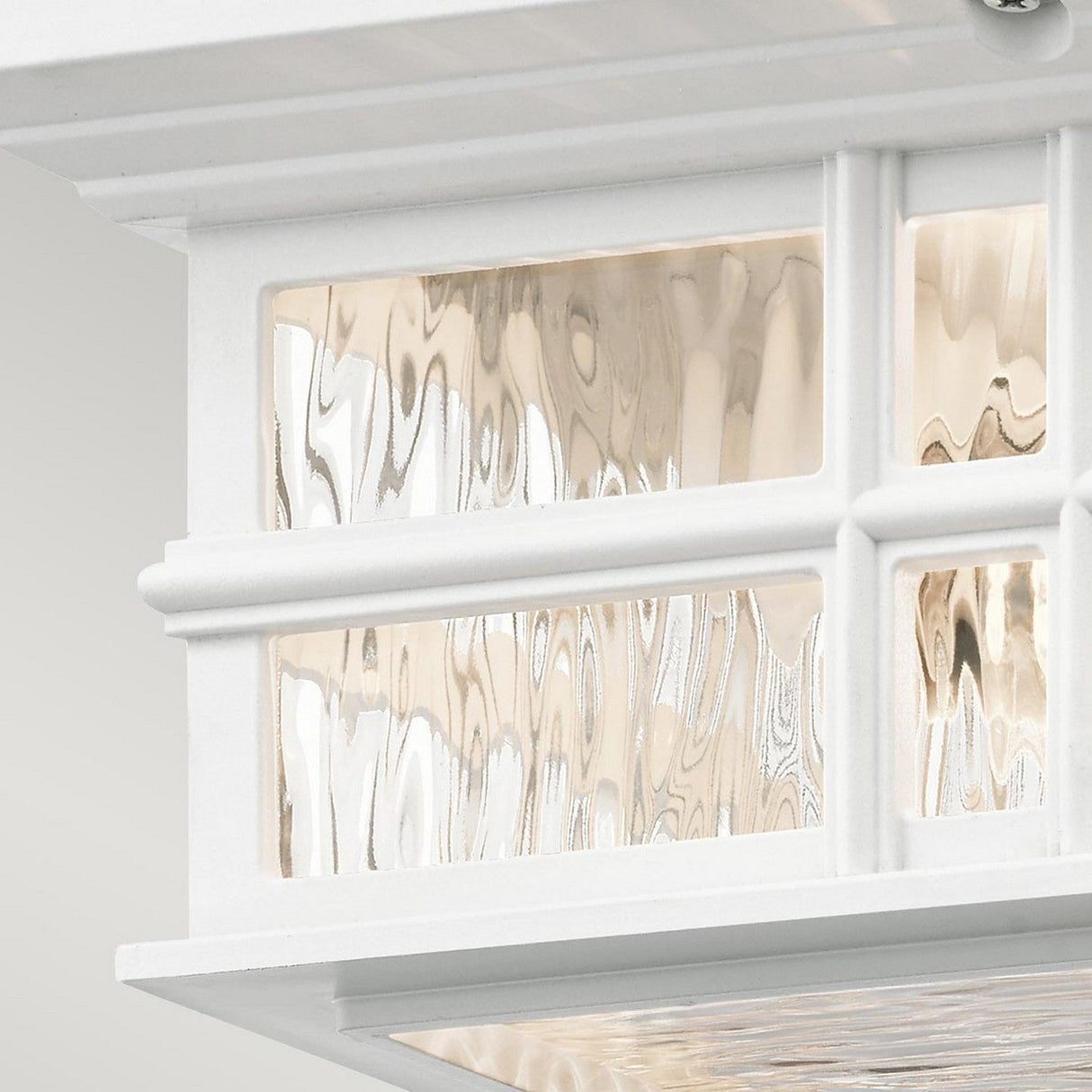 A close-up of the Beacon Outdoor 2 Light Flush - White showcases its decorative textured glass panels, featuring a wavy pattern that subtly distorts the view. This transitional design offers an elegant and classic touch, with soft light reflecting through its durable finish.