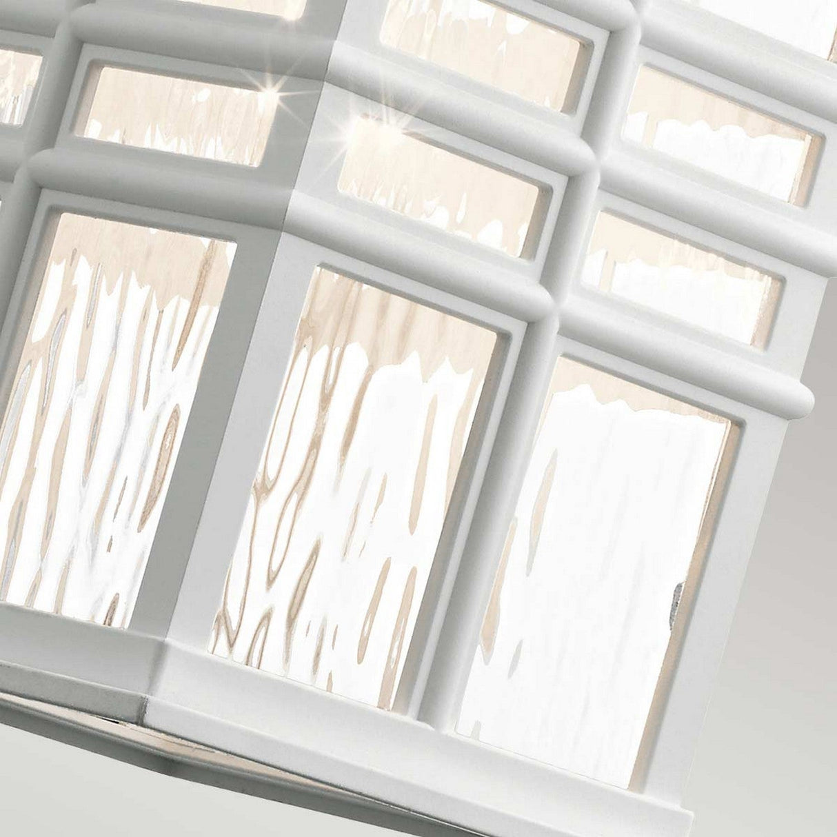 Close-up of a window with decorative frosted glass panes, showcasing a lattice design. Soft light from the nearby Beacon Square Outdoor 1 Light Medium Wall Lantern in white creates a shimmering effect on the glass, accentuating its textured pattern and adding an element of outdoor craftsman design elegance.