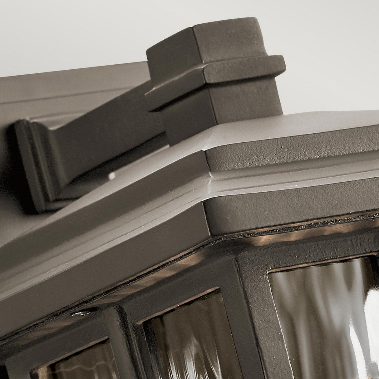 Close-up of the Beacon Square Outdoor 1 Light Small Wall Lantern in bronze, showcasing a craftsman-inspired design with modern fixtures and glass panes. Its sleek lines and muted color contribute to its contemporary aesthetic, making it an exquisite piece in outdoor lighting.