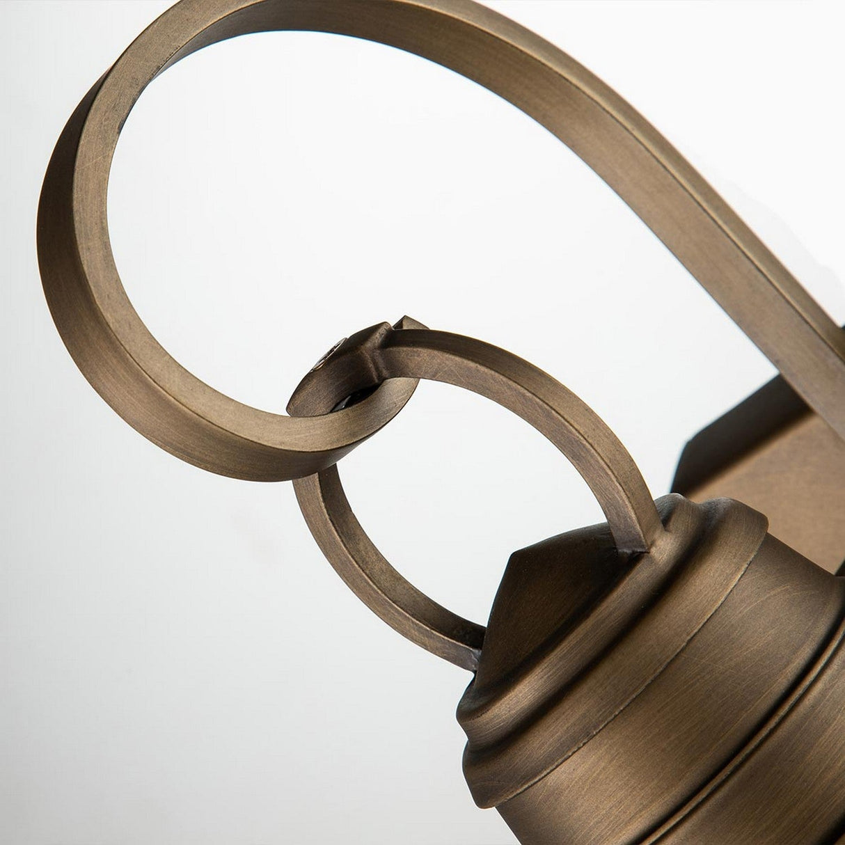 Close-up of a natural brass decorative scroll design on the Bridgepoint Outdoor 1 Light Small Wall Lantern, highlighting intricate curves and loops. The smooth, metallic surface features a brushed finish, adding an elegant touch to this nautical outdoor lighting piece.