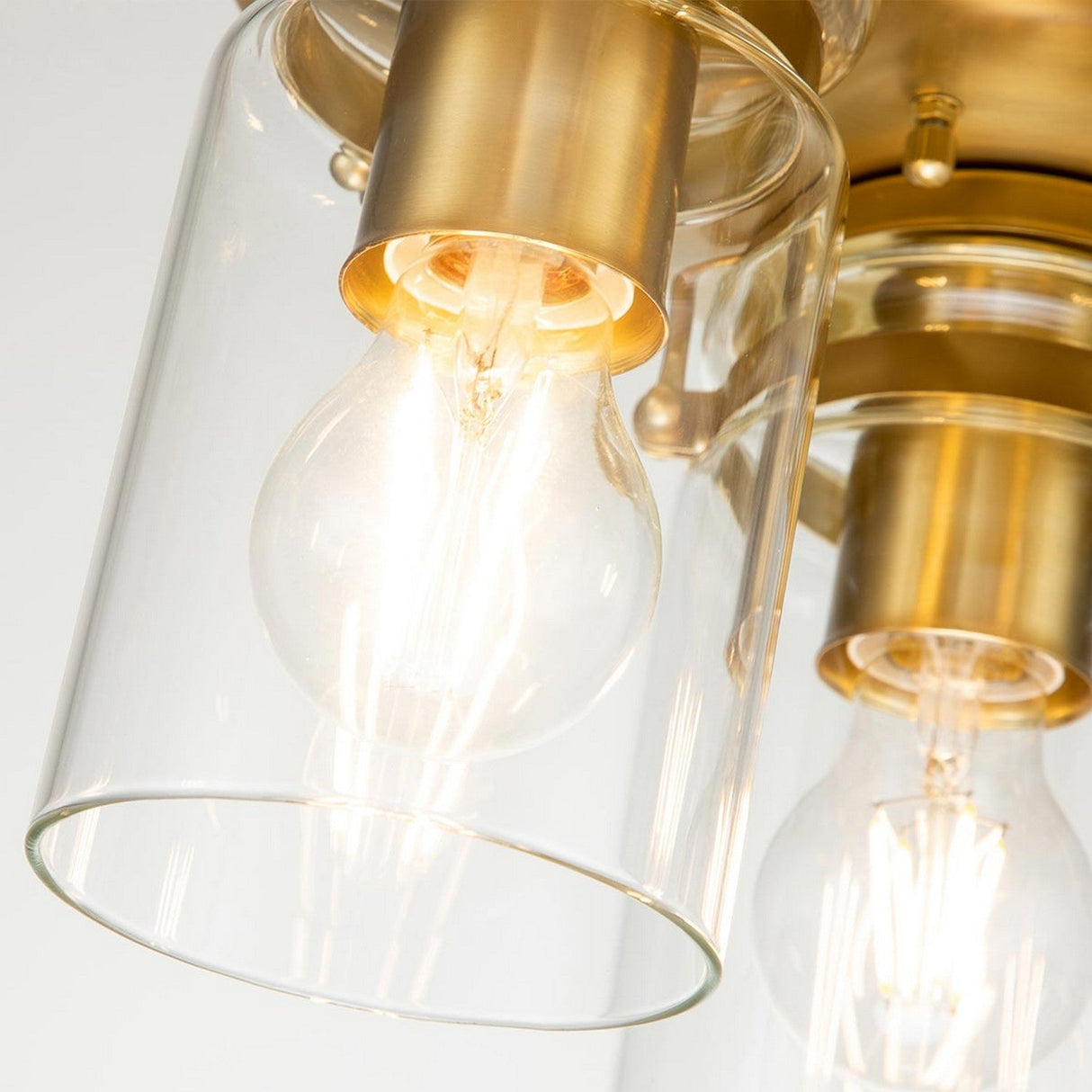 Featuring a vintage-inspired design, this modern light fixture showcases a clear glass shade and an incandescent bulb that emits a warm glow, emphasizing the brushed brass finish and elegant metallic details characteristic of the Brinley 3 Light Flush - Brushed Brass.