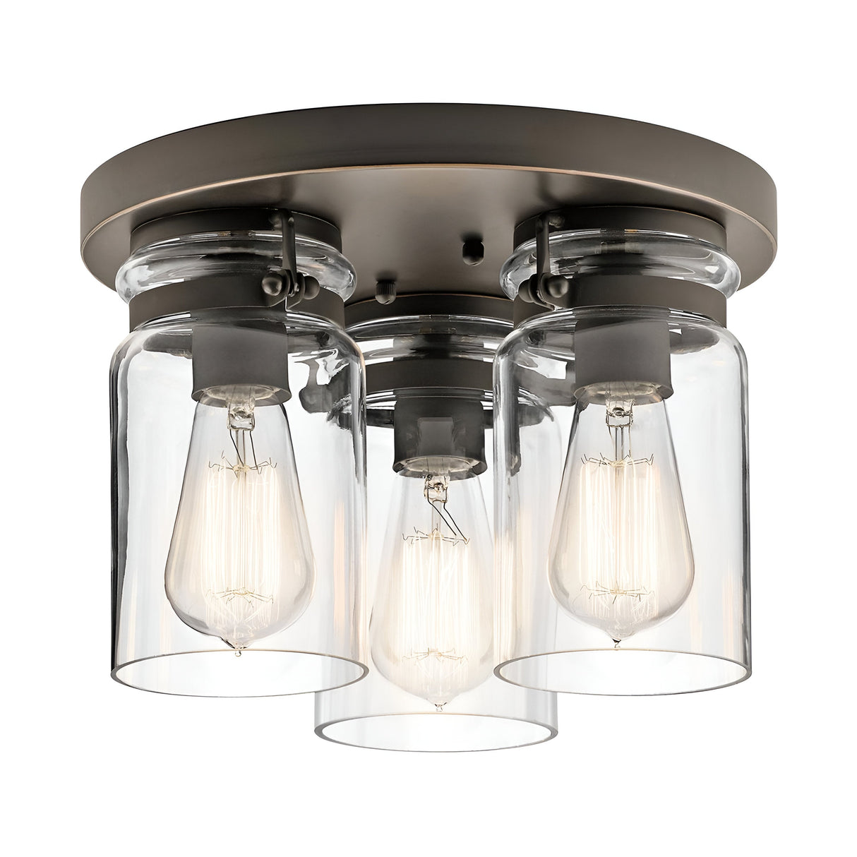 The Brinley 3 Light Flush - Bronze ceiling light fixture showcases a vintage-inspired design with its circular bronze base and three clear glass cylindrical shades. Each shade houses an exposed filament bulb, seamlessly blending industrial and modern aesthetics.