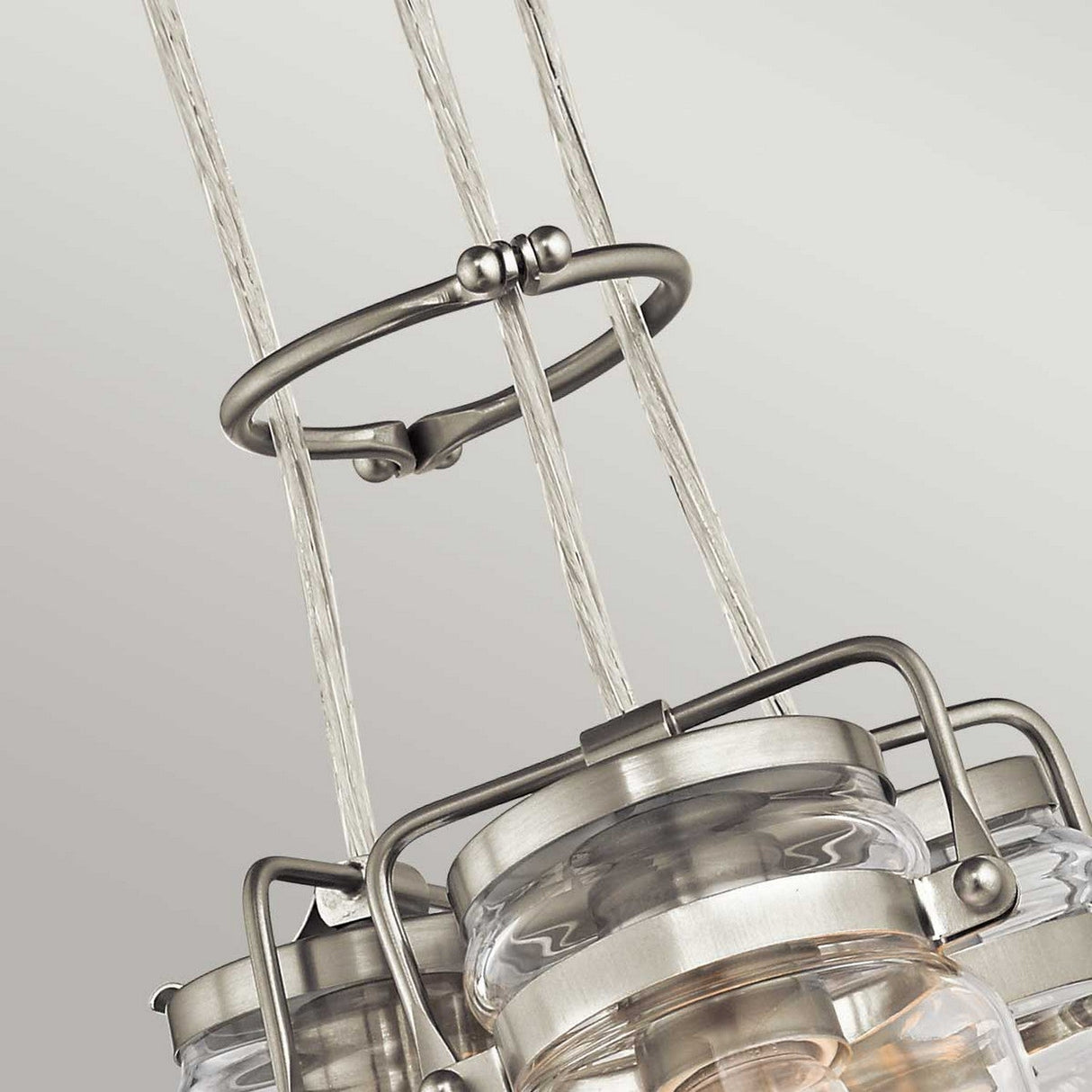 Here's a close-up of the Brinley 3 Light Pendant - Brushed Nickel, showcasing its clear glass and brushed nickel details that add a vintage flair. The pendant consists of three lights suspended from twisted cables connected to a circular metal ring, all displayed against a white background.