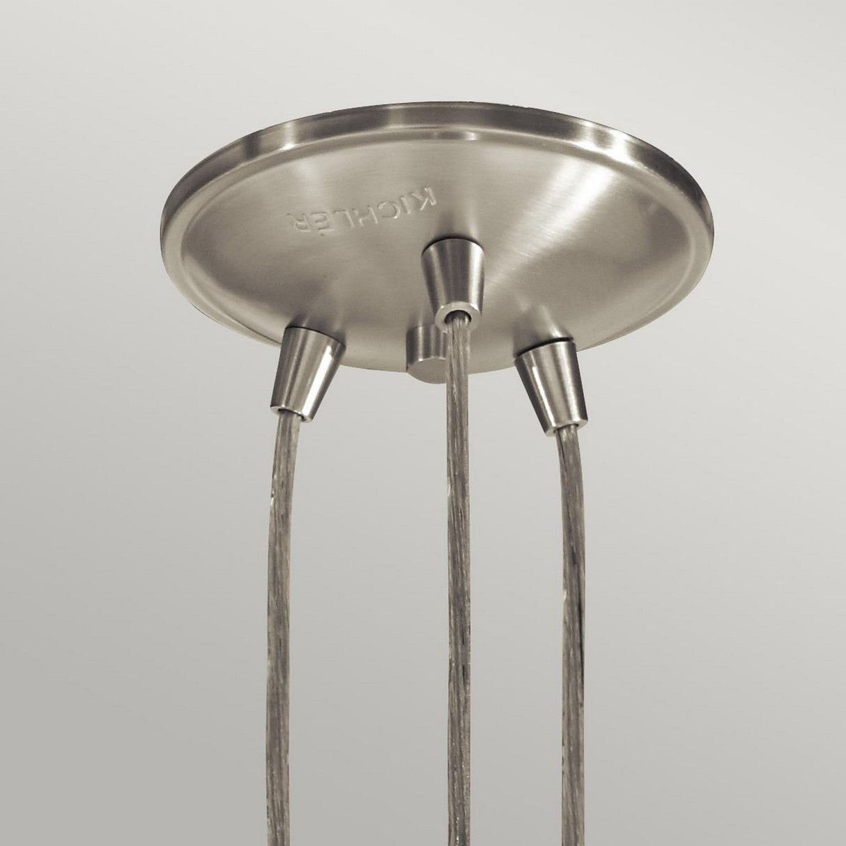 The Brinley 3 Light Pendant in brushed nickel showcases three distinct lighting features against a simple backdrop, exuding a sleek and vintage aesthetic. The brand name is tastefully engraved on its surface.