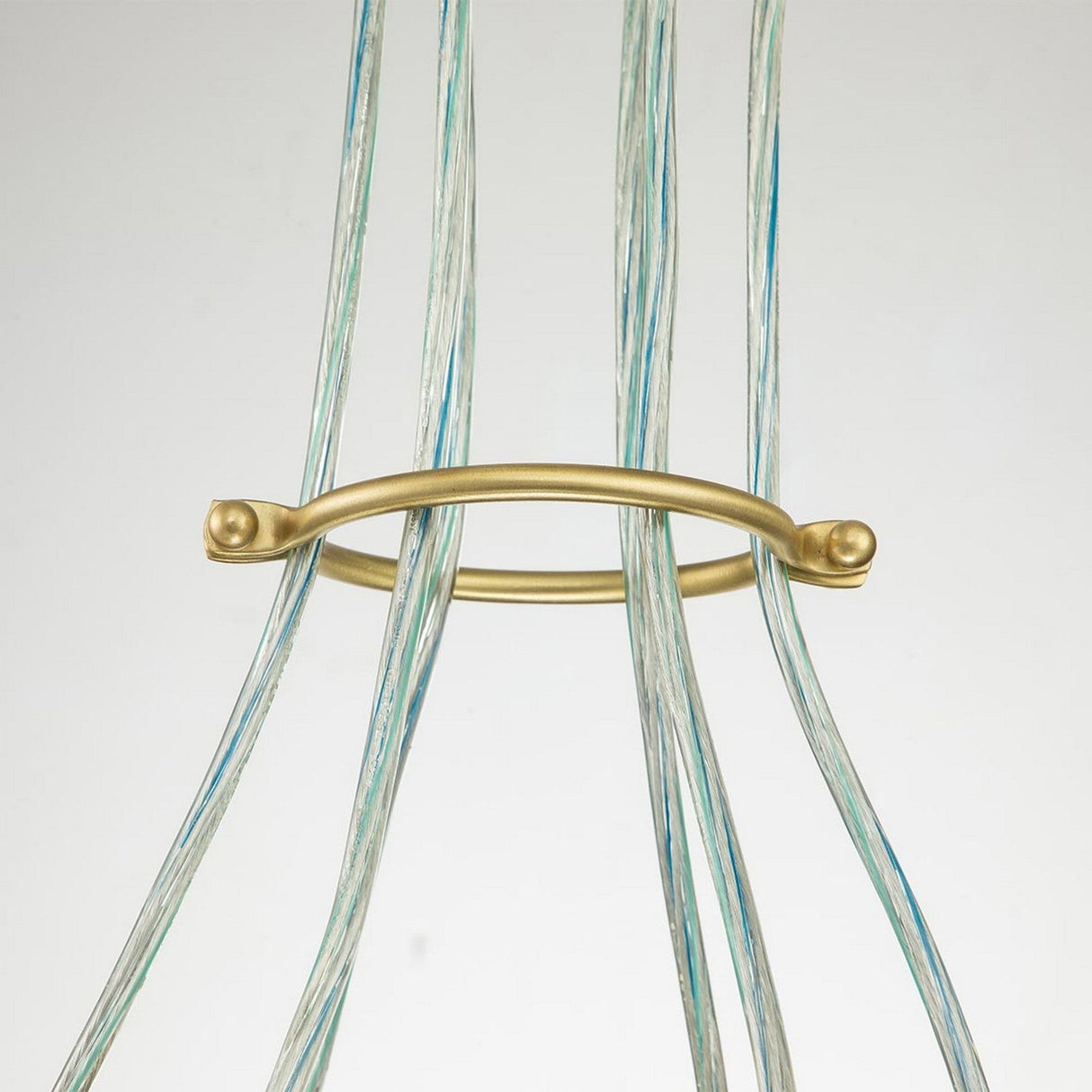 The Brinley 6 Light Pendant in brushed brass features several vertical, transparent rods accented with blue and white against a plain backdrop. These rods are evenly arranged around the handle, forming a symmetrical pattern that captures the elegance of mid-century modern lighting.