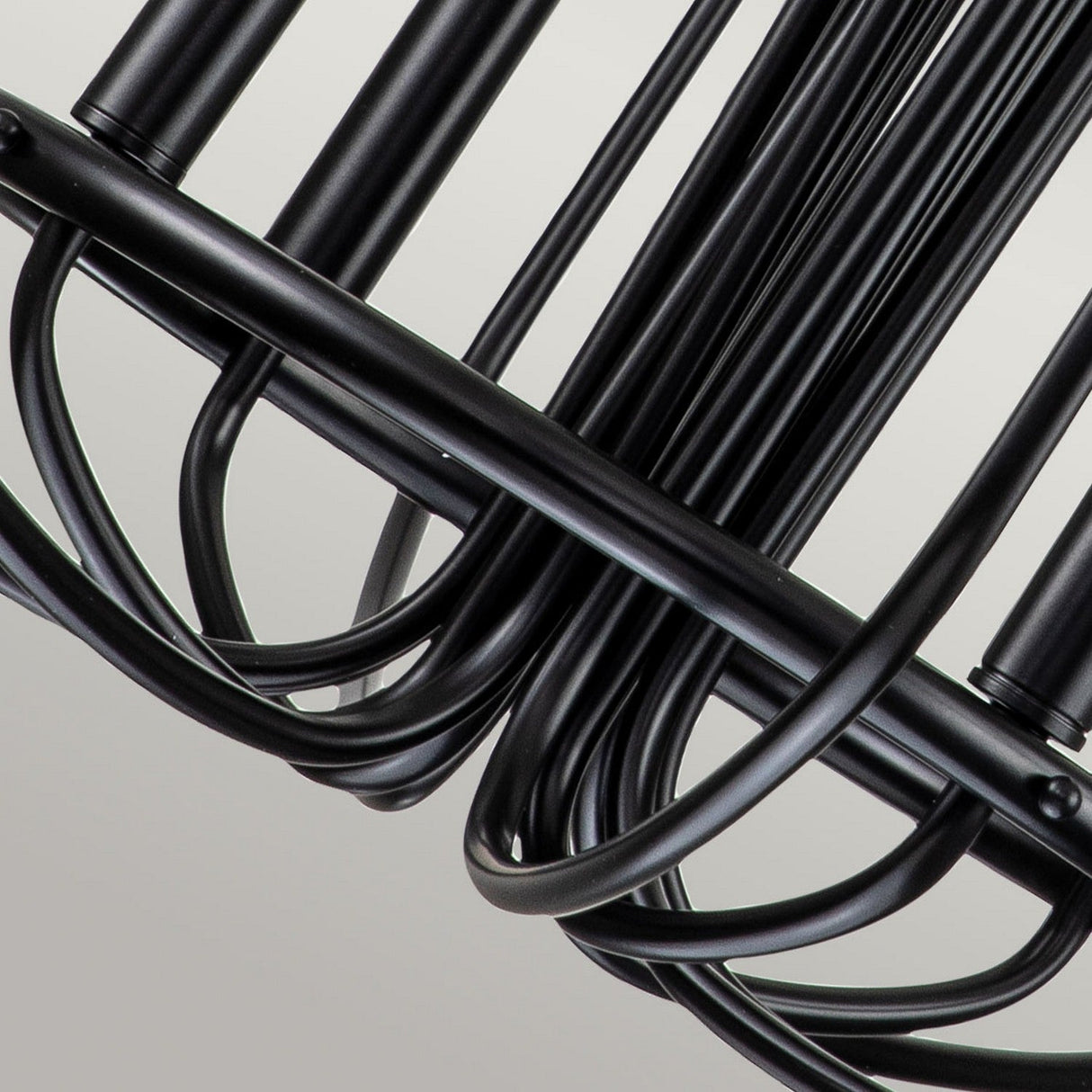A detailed view of the Capitol Hill 12 Light Chandelier - Black showcasing its black metal wire structure with curved, parallel lines that create an abstract geometric pattern against a neutral background.