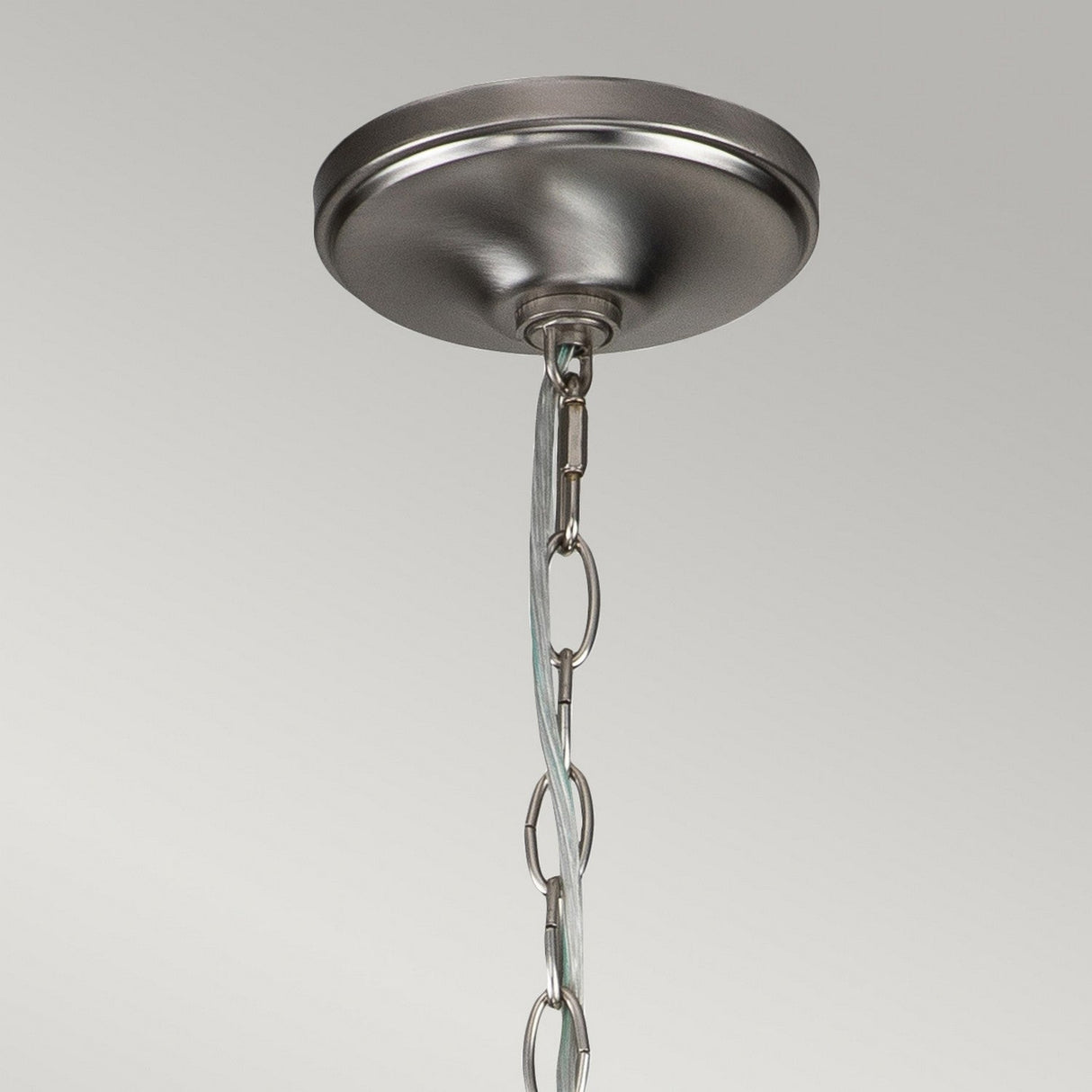 Close-up view of the Capitol Hill 12 Light Chandelier in brushed nickel, featuring a round base and a chain for suspension, set against a neutral gray backdrop.