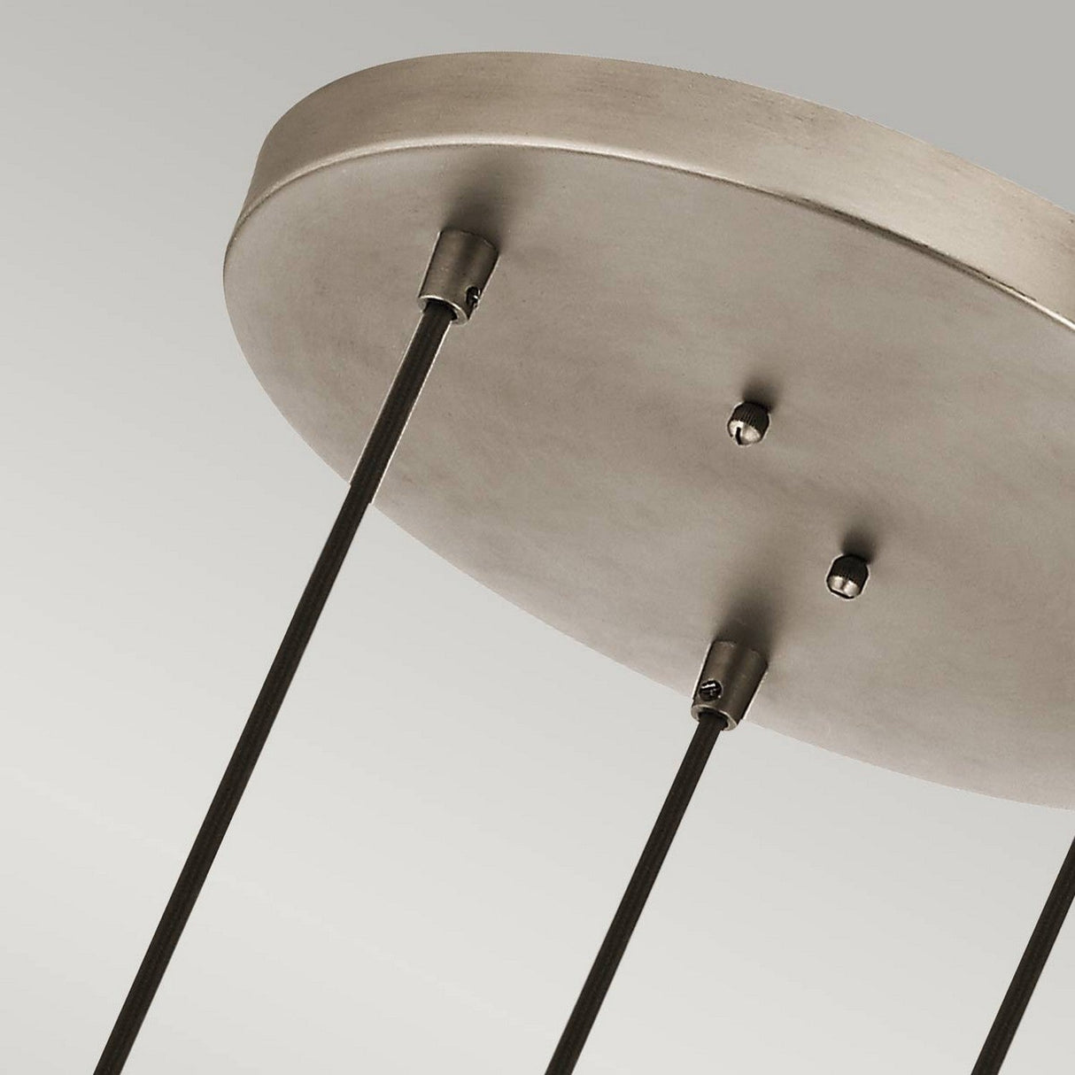 Close-up of a modern ceiling light fixture featuring the Ceiling Pan Round Ceiling Plate in a sleek Silver finish. Three dark rods elegantly extend downward, set against a simple grey background, offering versatile lighting solutions for any space.
