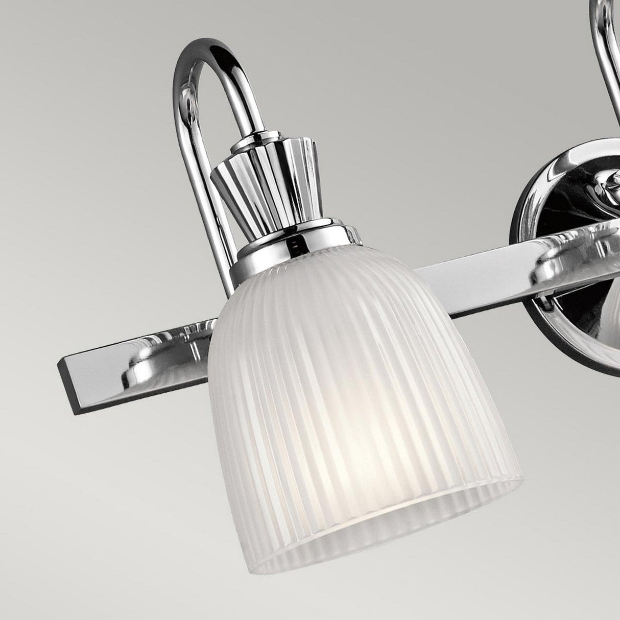 The Cora 3 Light Wall Light, with its IP44 rating, is perfect for bathroom use. This chrome wall-mounted fixture features a frosted glass shade that complements its sleek, modern design. The polished chrome finish enhances its elegant curved arm and ribbed detailing, casting a soft, diffused glow.