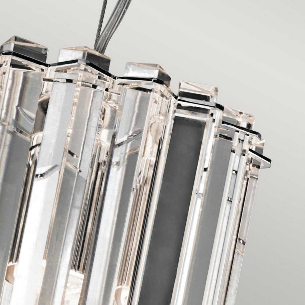 Close-up of the Crystal Skye 2 Light Mini Pendant in Chrome, showcasing a series of vertical, transparent glass panels within a reflective chrome frame. Elegant crystal prisms enhance its design as it gracefully hangs from sleek cables against a light gray background.