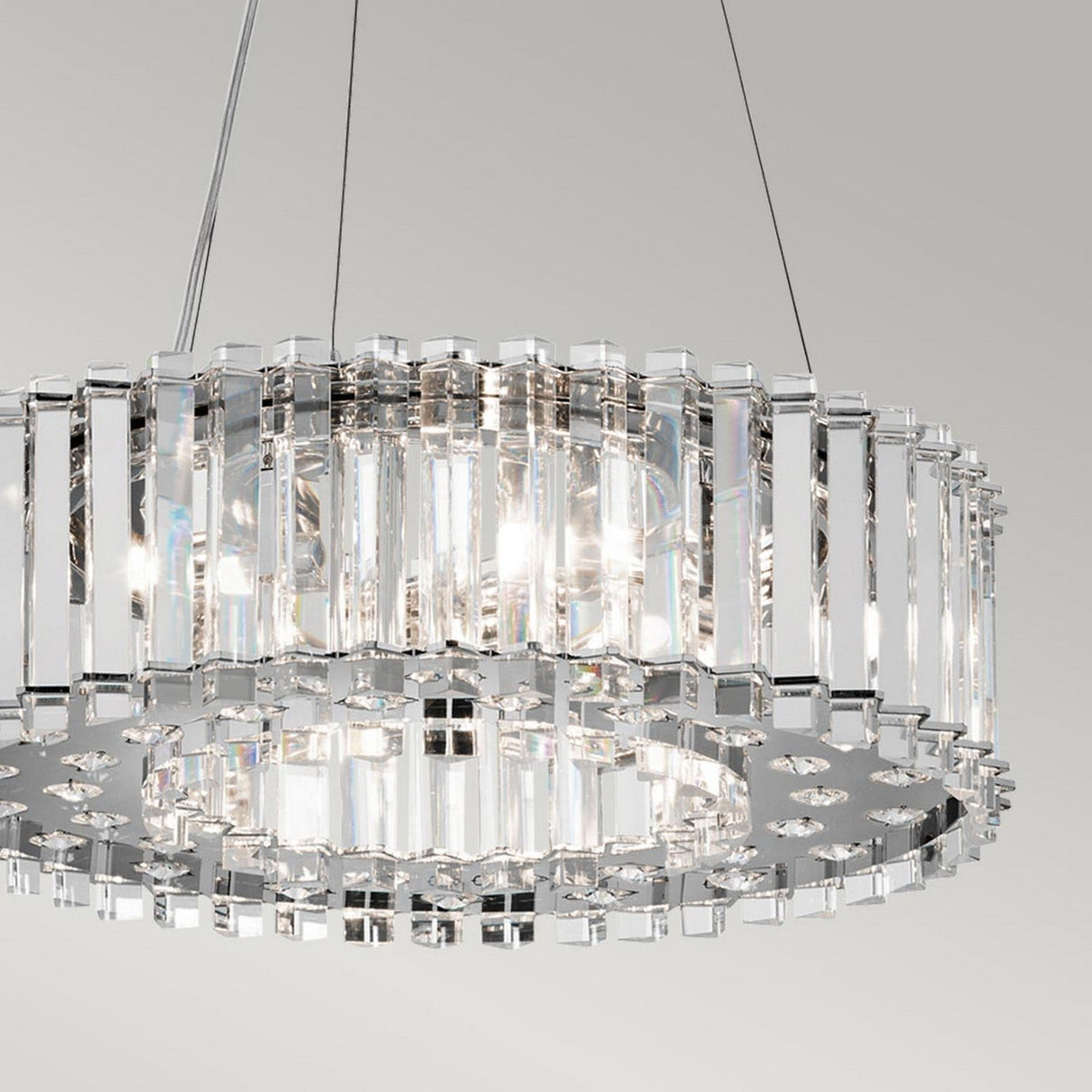 The Crystal Skye 6 Light Chandelier - Chrome features clear vertical crystal rods and chrome frame accents, hanging from thin wires. It emits soft light with a sophisticated circular design that looks elegant against a plain white background, enhanced by its LED compatibility.
