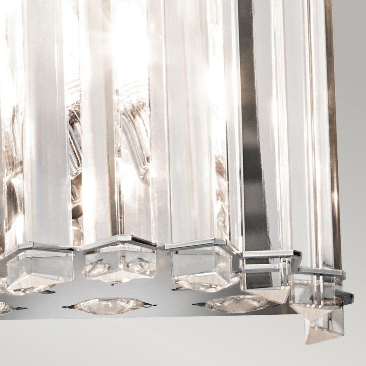 A close-up of the Crystal Skye 2 Light Wall Light - Chrome reveals its modern design with vertical glass panels that beautifully reflect light. Its angular shapes and polished chrome base exude elegance and sophistication.