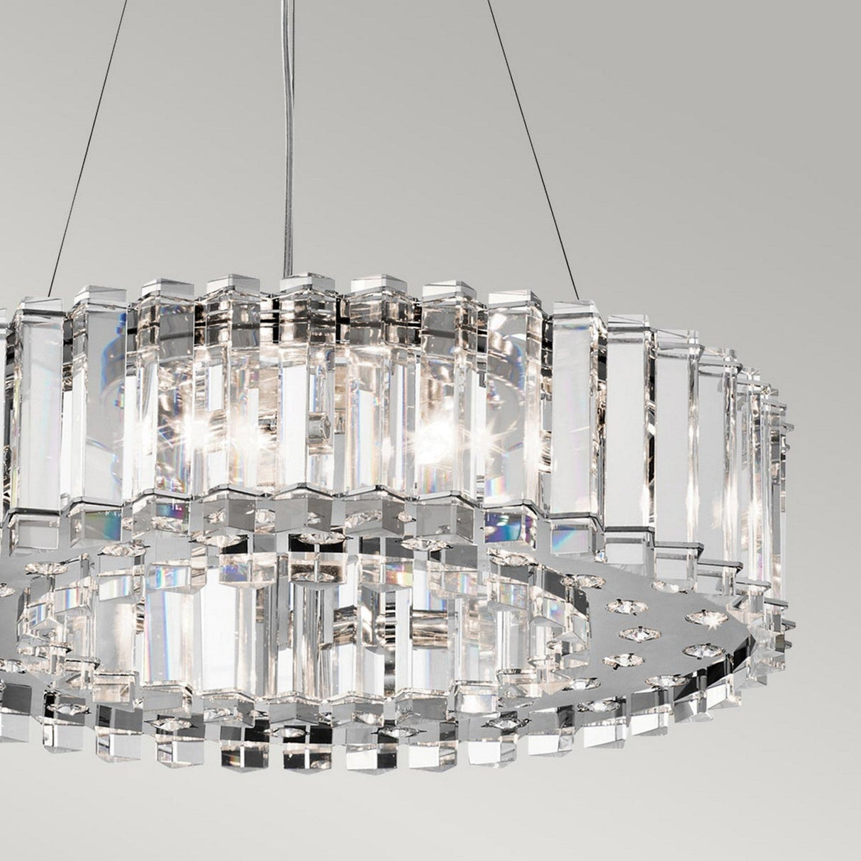 Presenting the Crystal Skye 8 Light Chandelier - Chrome: a luxurious lighting masterpiece. This contemporary fixture boasts two circular tiers adorned with triangular crystal prisms, creating a stunning light display. It is elegantly suspended from a metal support against a plain gray background, redefining sophistication.