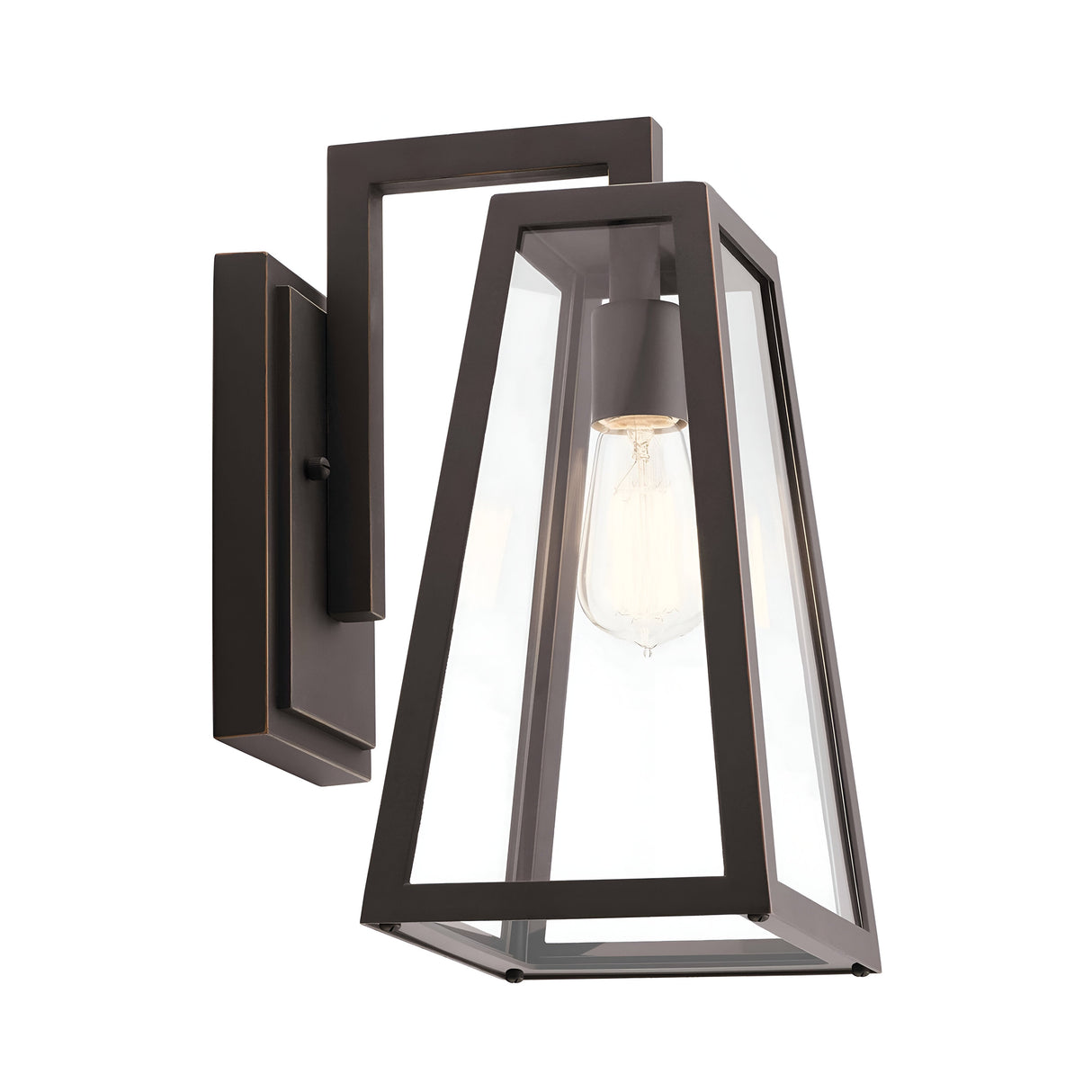 The Delison Outdoor 1 Light Wall Lantern in Rubbed Bronze features a modern geometric design with a black metal frame and clear glass panels, showcasing an exposed Edison-style bulb. This IP44-rated fixture adds a touch of rustic lodge exterior charm to any space.