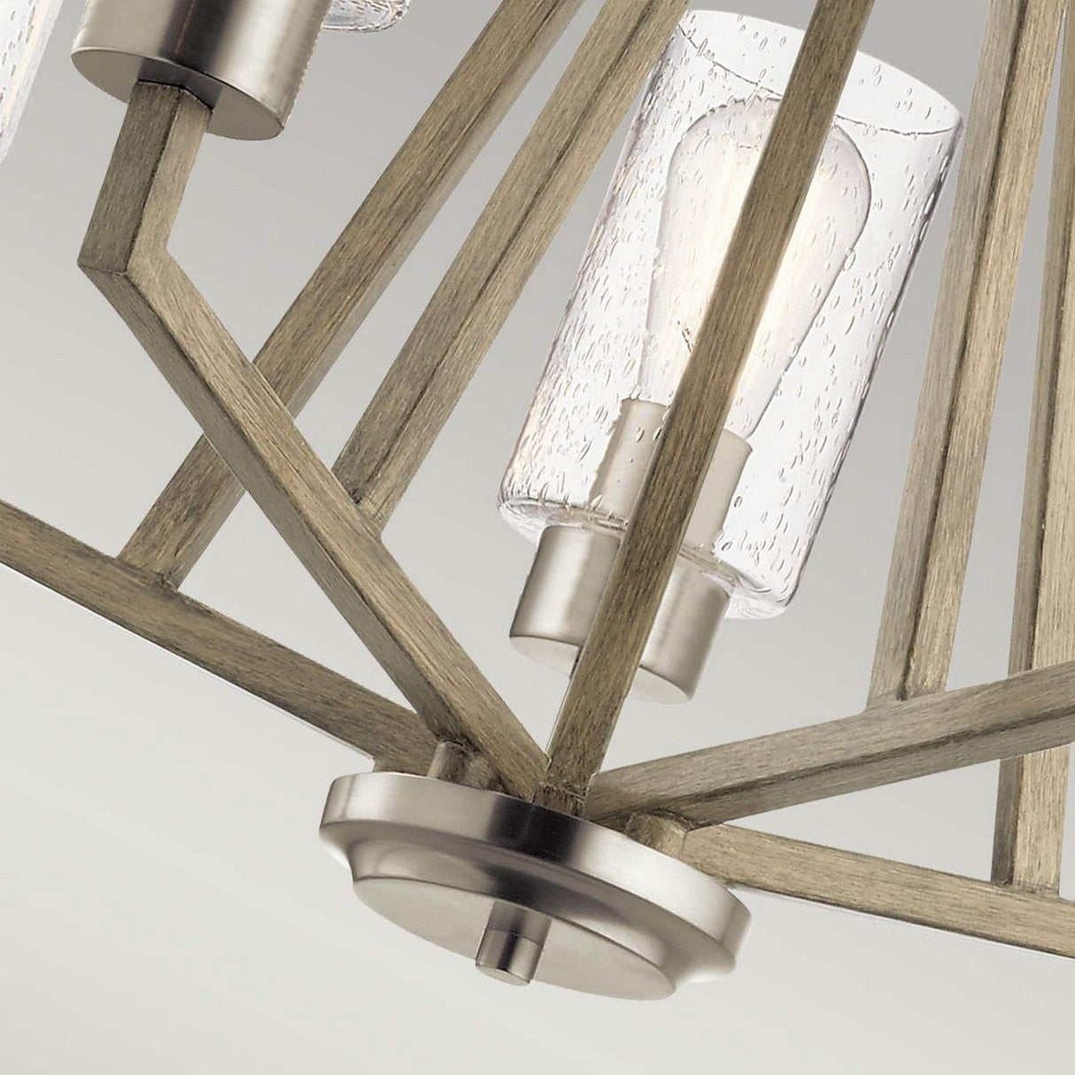 Close-up of the Deryn 5 Light Chandelier in Antique Grey, featuring a geometric wooden frame and clear glass shades encasing lightbulbs. The metal accents provide a striking contrast to the design, enhancing its rustic allure.