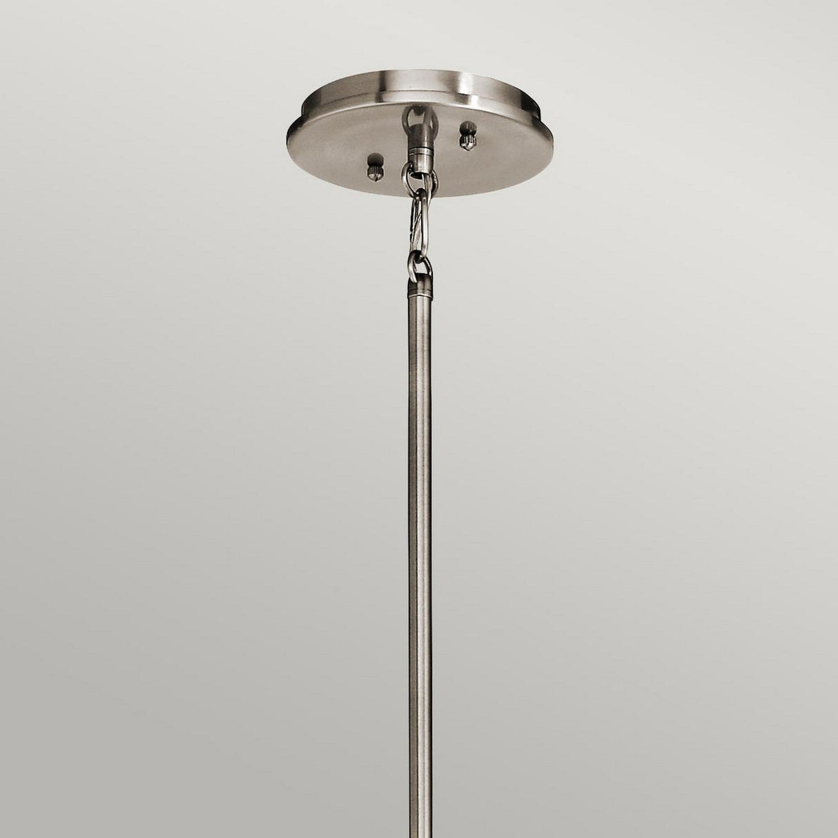 Featuring a sleek design, the Emory 4 Light Duo-Mount Chandelier in silver showcases a metal ceiling mount with a semi-flush style. It includes a rod suspended from a circular base, securely attached with screws against a neutral gray backdrop. The fixture exudes an incomplete look, hinting at its role as part of an elegant chandelier lighting solution.