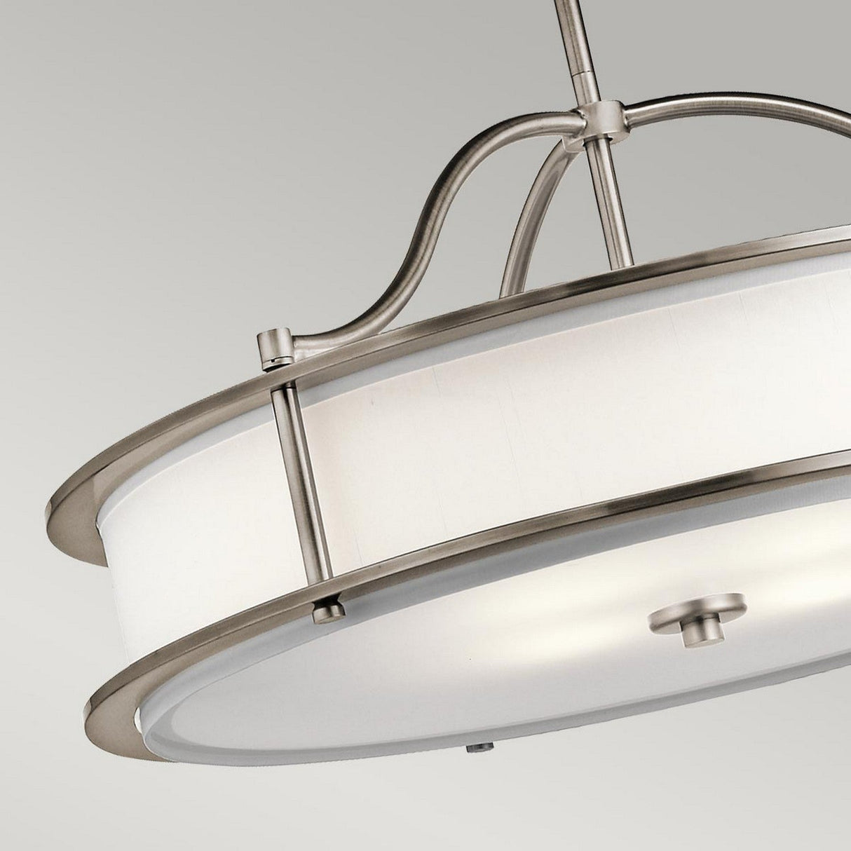 The Emory 4 Light Duo-Mount Chandelier - Silver features a sleek, silver finish with a brushed metal frame encircling its white cylindrical shade. The fixture is elegantly suspended by a metallic rod against a neutral gray backdrop.