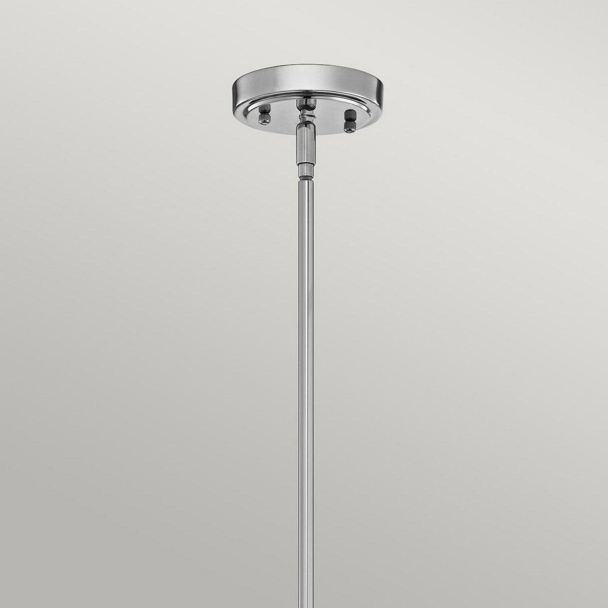 A close-up view of the Everly 1 Light Medium Pendant in chrome highlights its sleek design, similar to a contemporary pendant. Set against a plain, light gray background, this elegant fixture gracefully extends downwards from the circular ceiling mount.