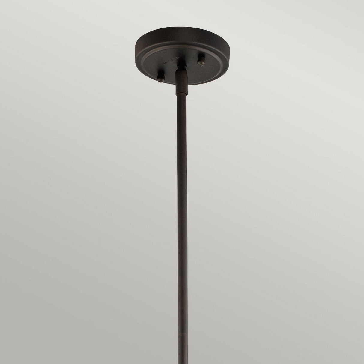 The Everly 1 Light Small Pendant - Olde Bronze showcases a sleek black design, gracefully hanging against a light gray backdrop. Its minimalist and modern style is accentuated by a delicate seeded glass shade, perfectly paired with an Olde Bronze finish.