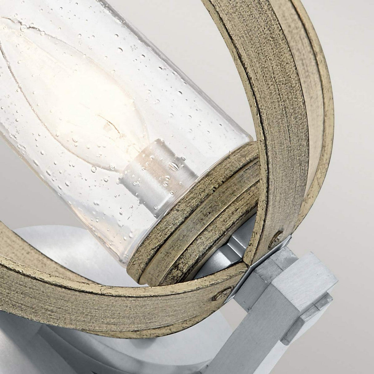 This close-up features the Grand Bank Outdoor 1 Light Wall Light, highlighting a clear glass bulb encased in a cylindrical cover. The fixture is IP44 rated for safety and boasts concentric wooden rings in antique grey and brushed aluminium, which enhance its rustic design against the neutral background.
