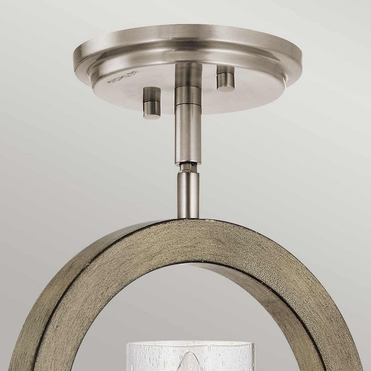 The Grand Bank 1 Light Wall Light in Antique Grey beautifully highlights its circular metallic base and curved wooden accent, seamlessly merging rustic charm with modern design. Its cylindrical frosted glass shade adds a sleek touch to the overall aesthetic.