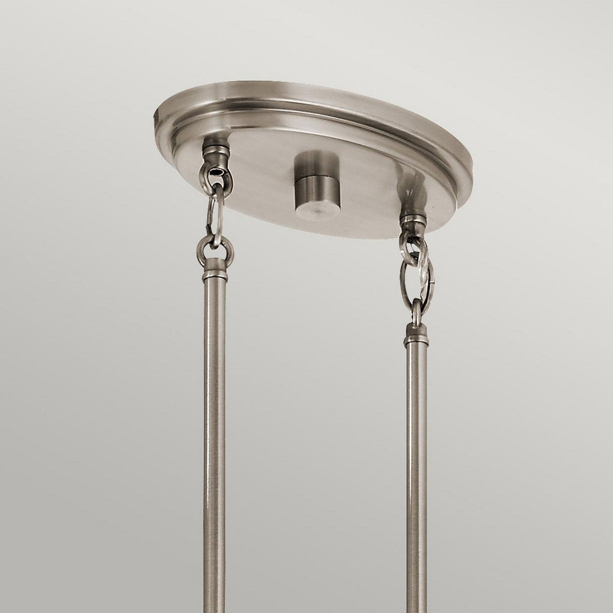 A close-up view of the Grand Bank 5 Light Chandelier in Antique Grey showcases a minimalist, modern take on a rustic chandelier. Its sleek design features metal loops connecting two metal rods to a round base, set against a plain background.