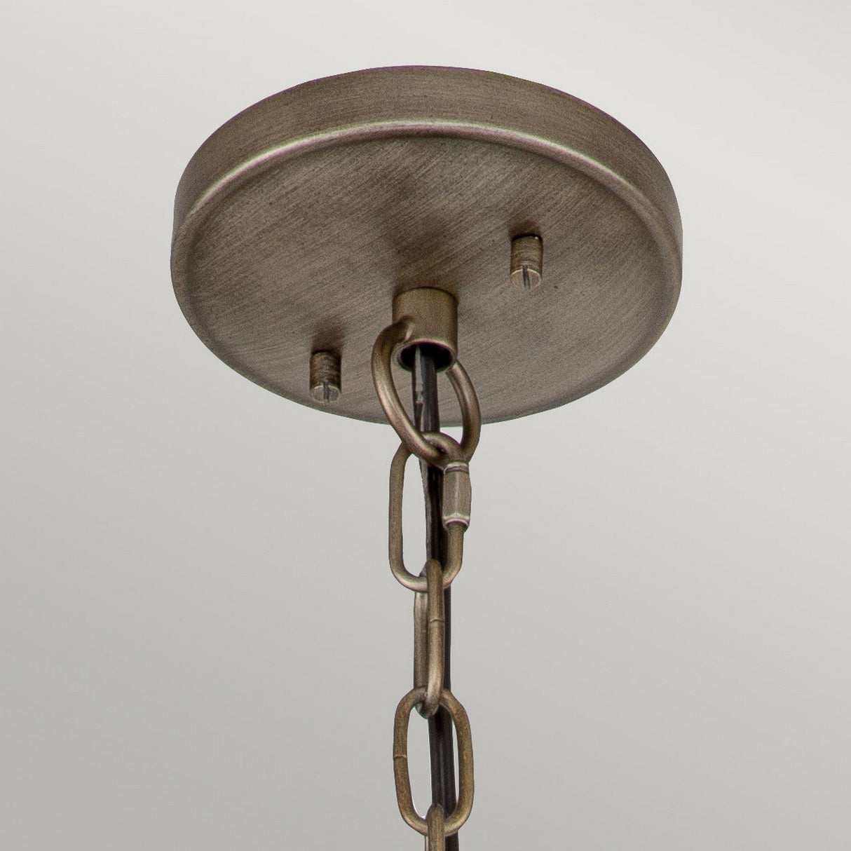Close-up view of a metallic ceiling mount with a chain hanging down, reminiscent of a Victorian-inspired lantern. The mount features a circular base and thick, sturdy chain links, designed for supporting the Halleron Outdoor 3 Light Chain Pendant in Burnished Bronze. The surface boasts an antique brass finish.