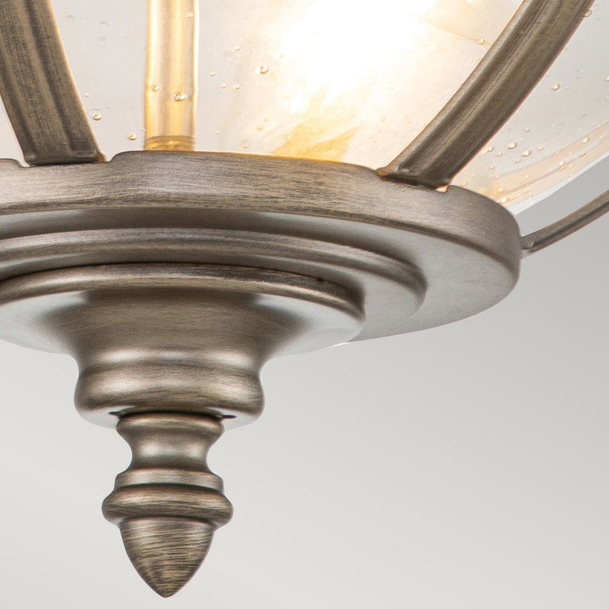 Close-up of the Halleron Outdoor 3 Light Ceiling Flush with a frosted glass dome. This fixture showcases a Victorian-style design, complete with decorative detailing such as a finial at the bottom, and its burnished bronze finish emits a warm glow.