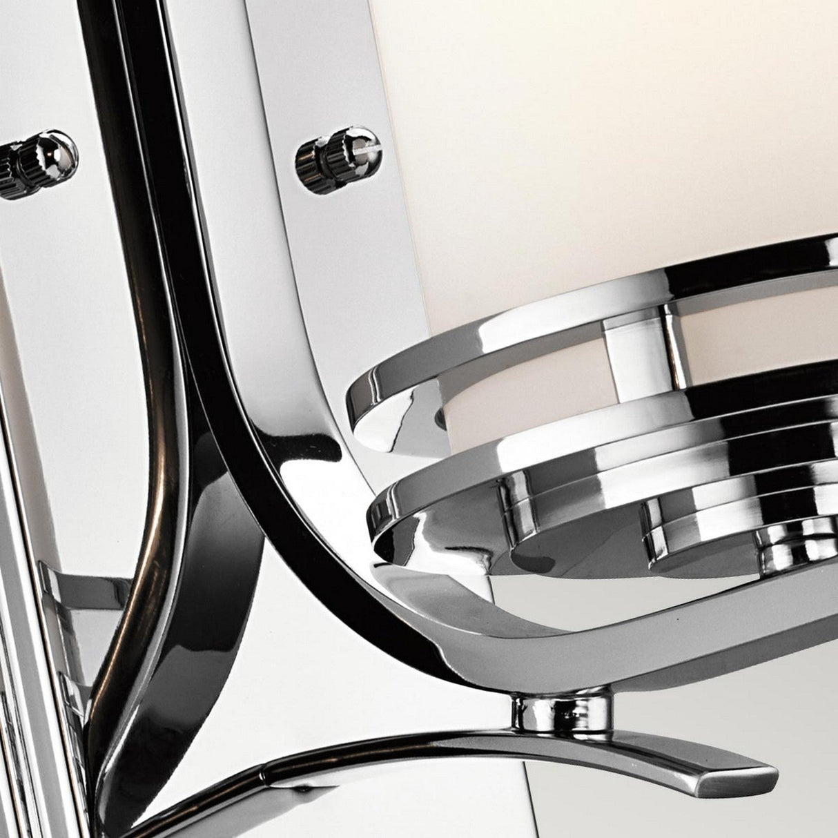 Close-up of the Hendrik 1 Light Wall Light in polished chrome, featuring sleek, curved lines and a circular design. The polished chrome surface reflects light beautifully, enhancing its modern elegance and contemporary style—an ideal choice for sophisticated bathroom lighting.