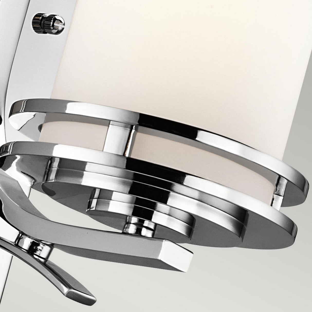 Close-up image of the Hendrik 1 Light Wall Light in polished chrome, featuring a sleek cylindrical frosted glass shade. This bathroom lighting design incorporates geometric elements for a look of modern elegance.