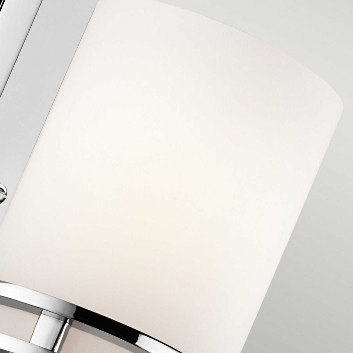 The Hendrik 1 Light Wall Light in polished chrome features a cylindrical white lampshade, exuding modern elegance against a light gray background—ideal for enhancing bathroom lighting.