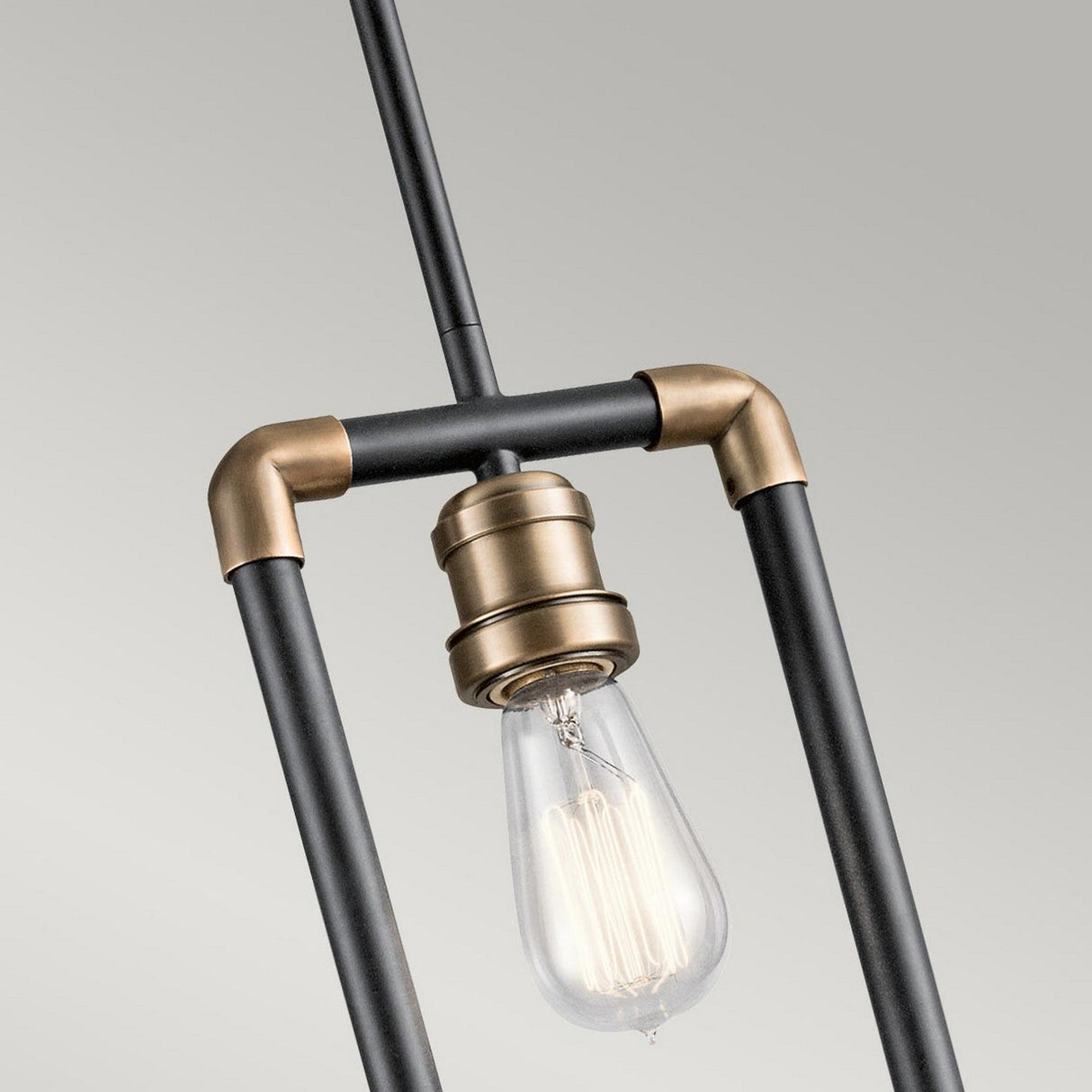 Close-up of the Imahn 1 Light Mini Pendant - Black & Natural Brass, highlighting its sleek black frame with natural brass accents and an Edison-style LED filament bulb that adds an industrial flair, all set against a light gray background.