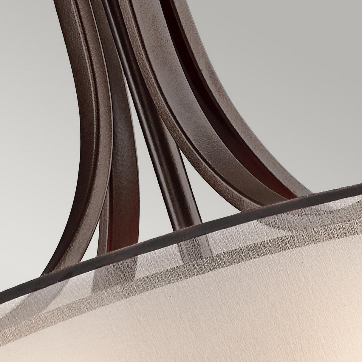 Close-up of the Lacey 4 Light Large Pendant in bronze, featuring gracefully curved arms over a fabric lampshade. Set against a soft gray background, the chandelier's sleek texture and double-shade design enhance its contemporary elegance.