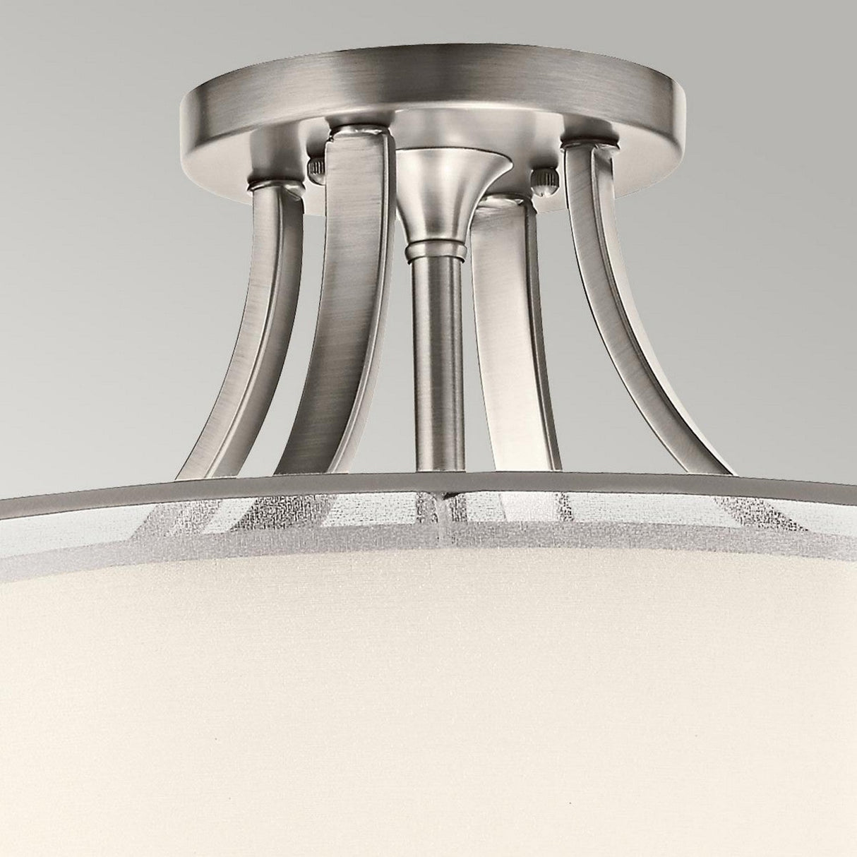Close-up of the Lacey 4 Light Semi Flush ceiling light fixture in silver, featuring gracefully curved metal arms. The double-shade design incorporates frosted white shades that provide an elegant contrast to the metallic hardware, all set against a neutral background.