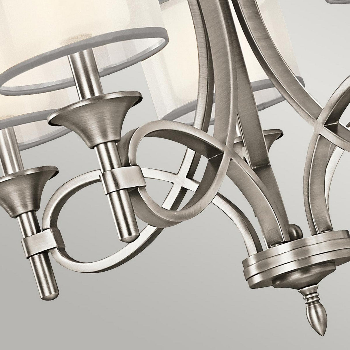 Close-up of the Lacey 5 Light Chandelier - Silver, featuring elegant lighting with graceful curved lines and intricate details. The design includes a double-shade feature, housing three candle-shaped light fixtures with lightly frosted shades, beautifully set against a neutral backdrop.