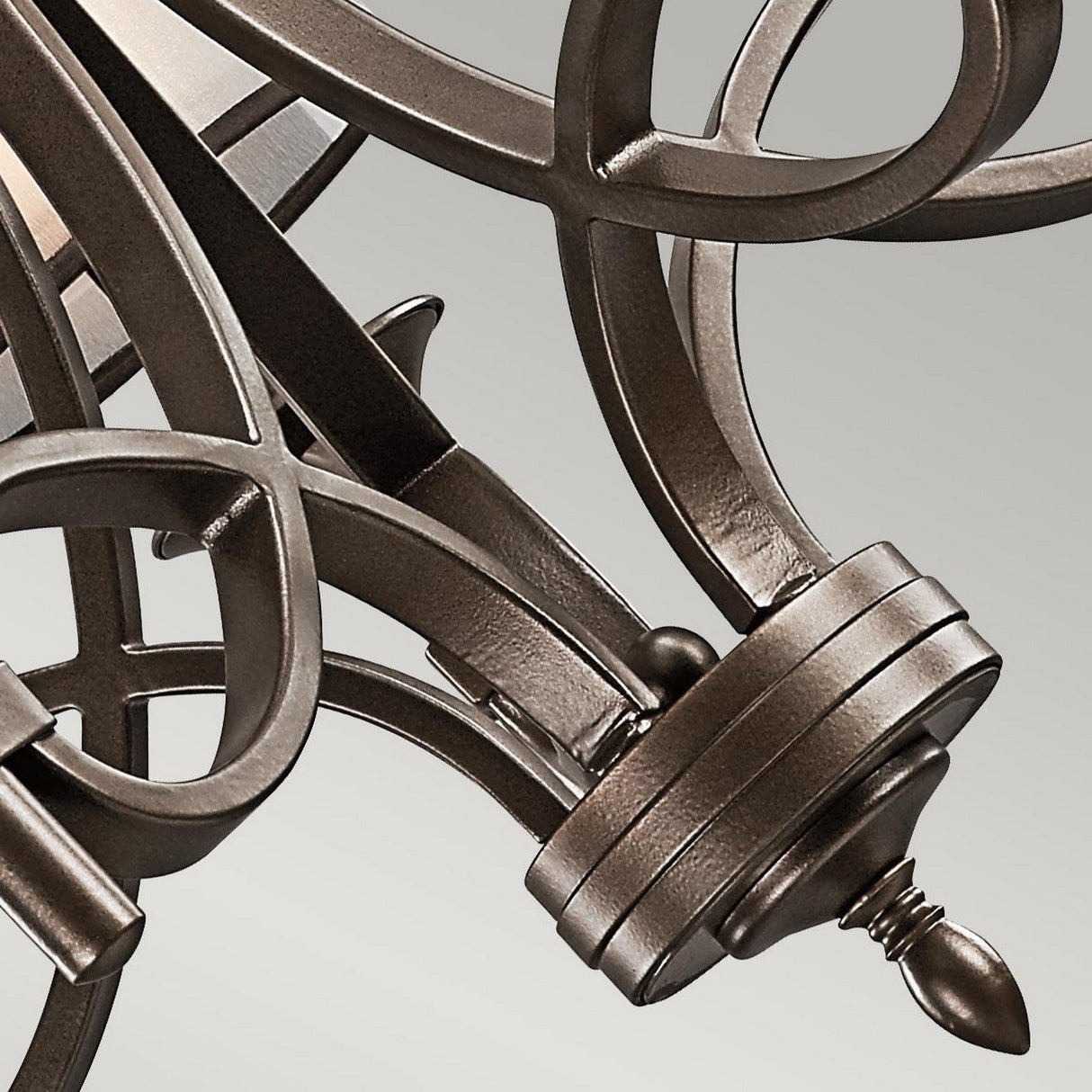 Close-up of the Lacey 5 Light Chandelier - Bronze, showcasing its ornate arm with decorative scrollwork and brushed finish, ideal for transitional interiors. The elegant curves and detailed craftsmanship highlight the chandelier's classic design against a gray background.